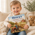 May include: A hardcover children's book titled Henry's Alphabet Farm Adventure. The cover features an illustration of a brown bear wearing a straw hat and blue overalls driving a red tractor, pulling a trailer filled with vegetables near a red barn.